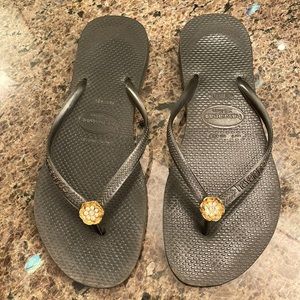Used- Black Havaianas with rhinestone flower. Black and gold.